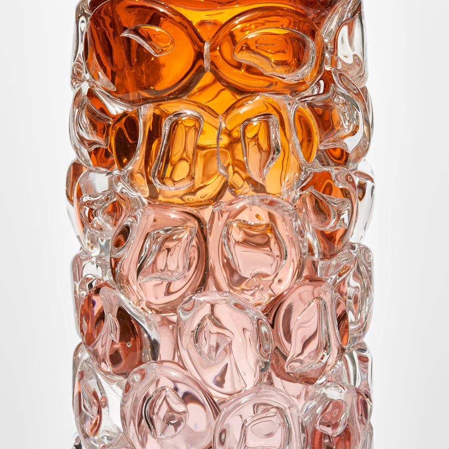 tubular clear vase with transparent base fading to pink and then bright rich orange at the top with the outer surface covered in oversized squished bubbles like bubblewrap handmade from glass