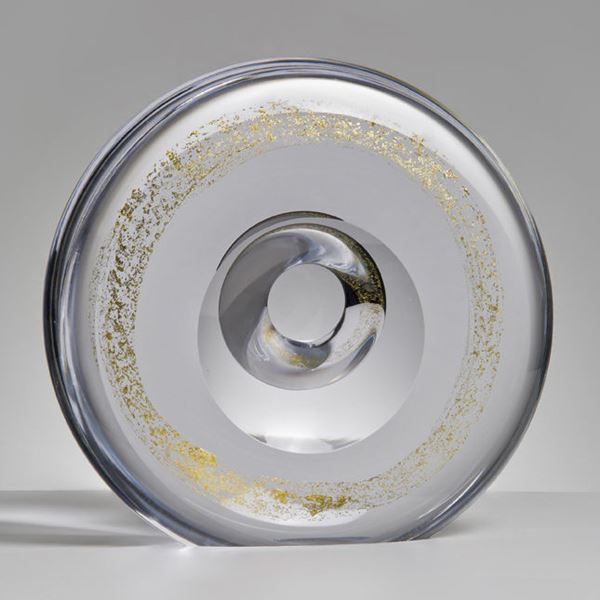 clear minimalist glass sculpture in the shape of a donut with spinkles of gold around the centre