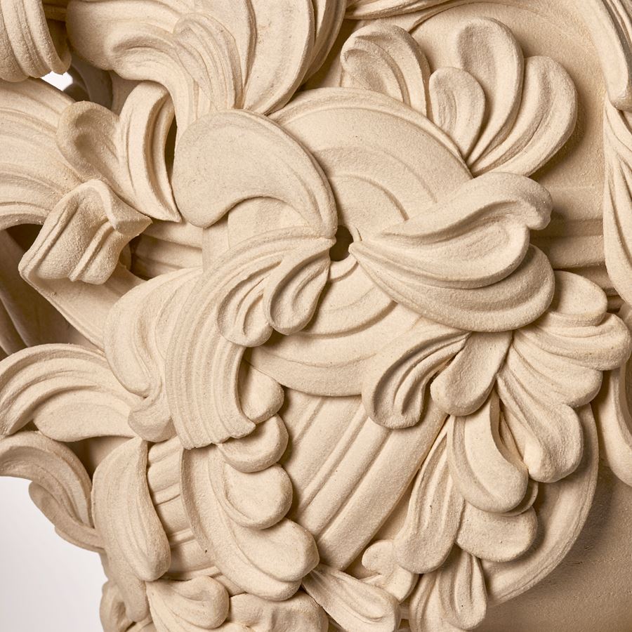 tall architectural ceramic sculptural vessel with handles with the appearance of weather worn sandstone covered in busy adornment of swirls and flourishes hand made from white st thomas clay
