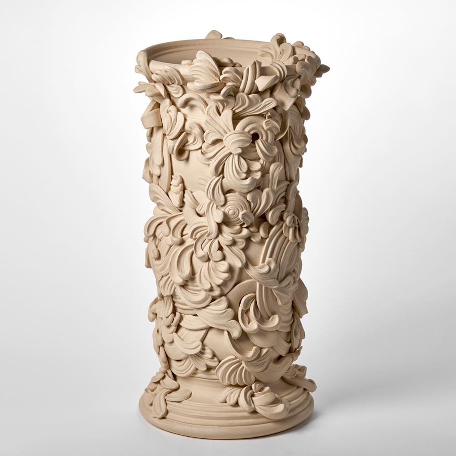 tall architectural vessel with the appearance of weathered sandstone covered in flourishes and swirls hand thrown and sculpted from white st thomas clay