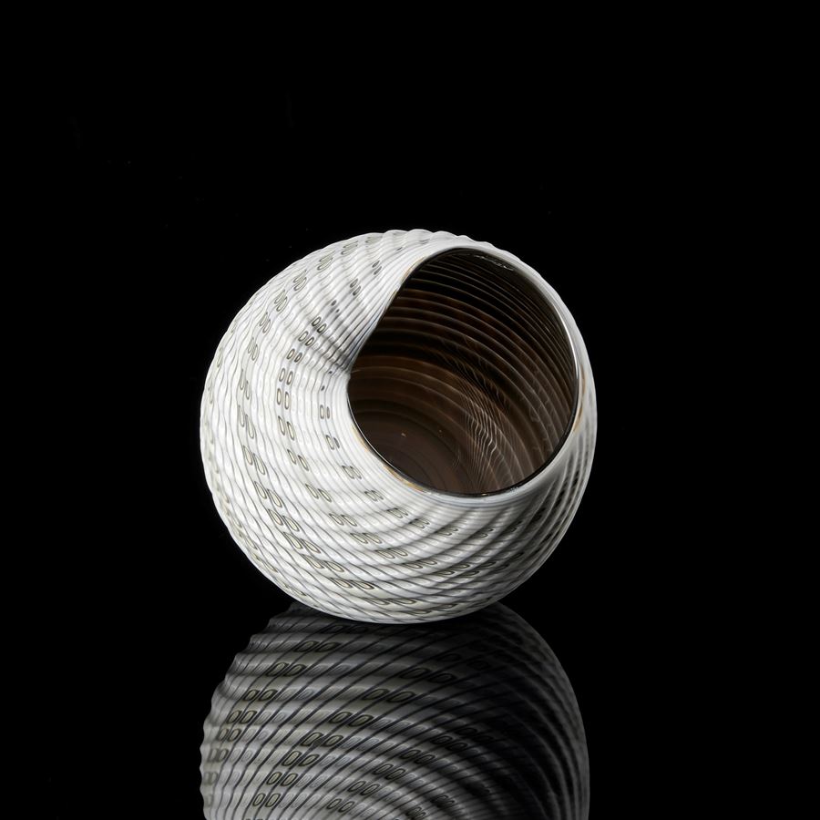 abstract round shell like vessel with matt exterior with incised cut surface in bands of white light grey blue and bronze with glossy interior hand made from glass