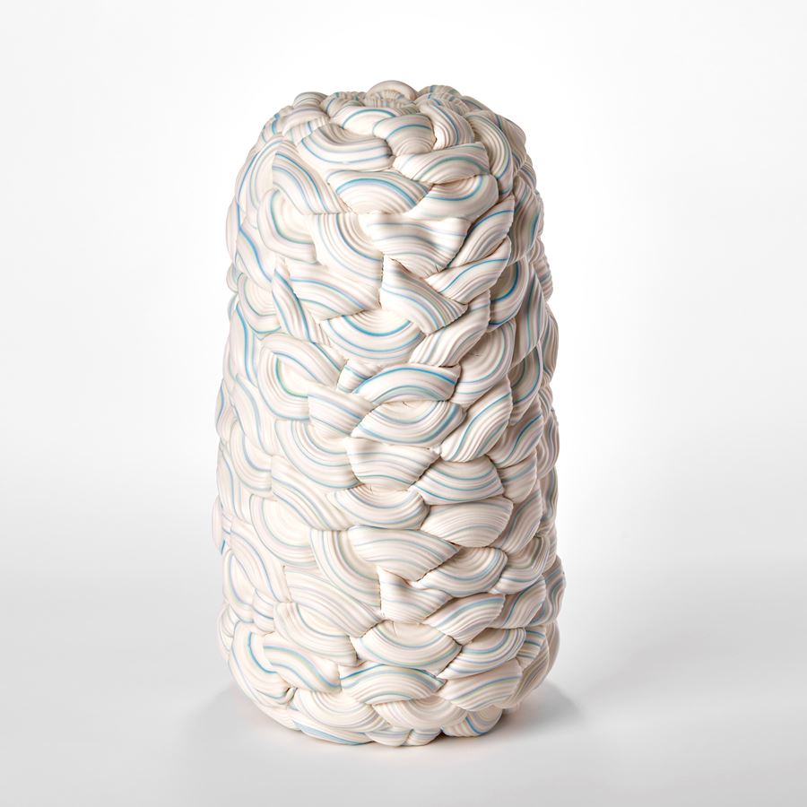 stacked sculpture consisting of interwoven ridged rings of white with bands of colours in turquoise yellow and pink with central seam and in two halves mirroring each other