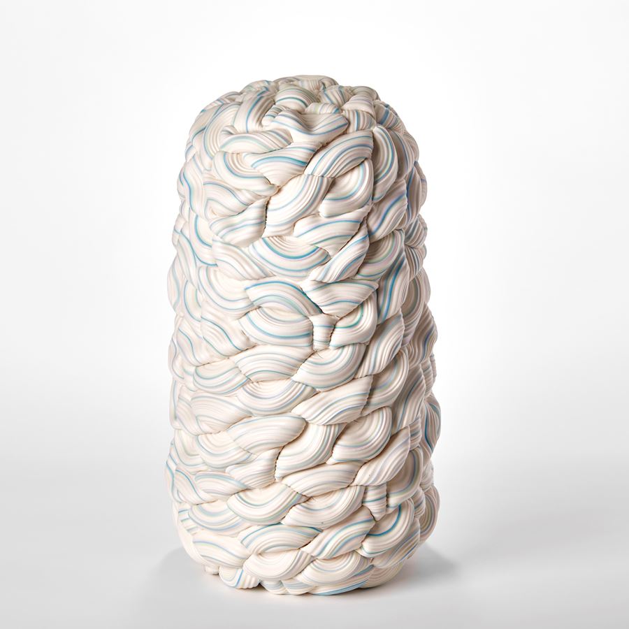 stacked sculpture consisting of interwoven ridged rings of white with bands of colours in turquoise yellow and pink with central seam and in two halves mirroring each other