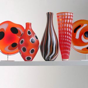 collection of five red art glass sculptures in different shapes with black and white patterns