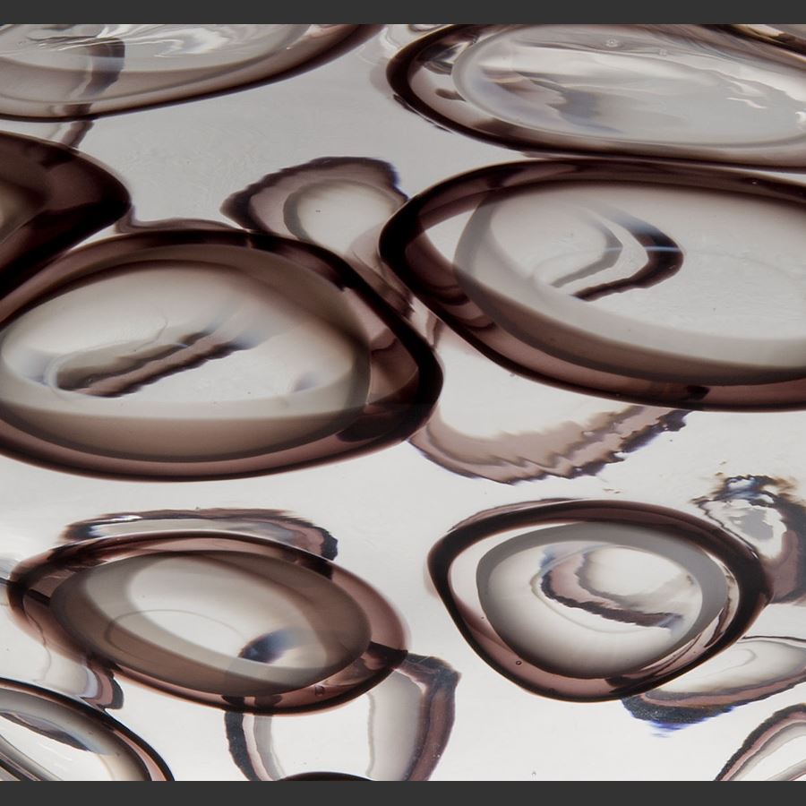abstract wide-shaped decorative glass sculpture in clear with large dark brown circle patterning throughout