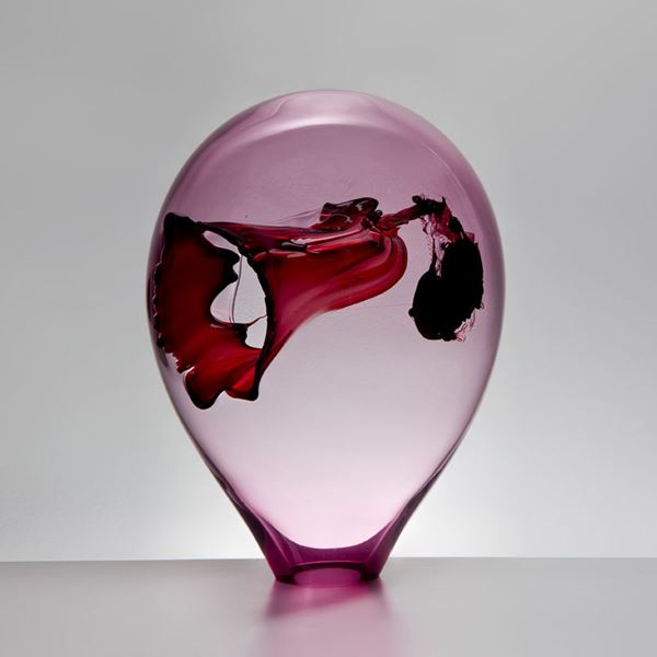 bubble shaped seethrough pink glass art sculpture with intricate interior red and black detail