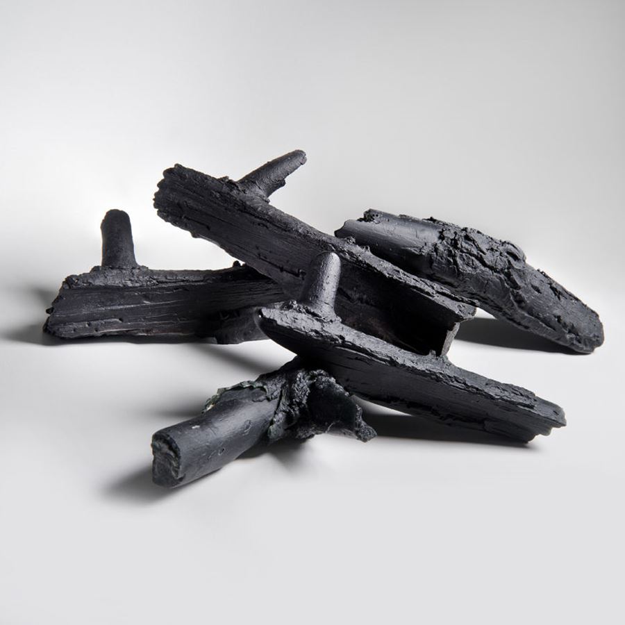 artwork of naturally arranged sculpted black logs made from glass 