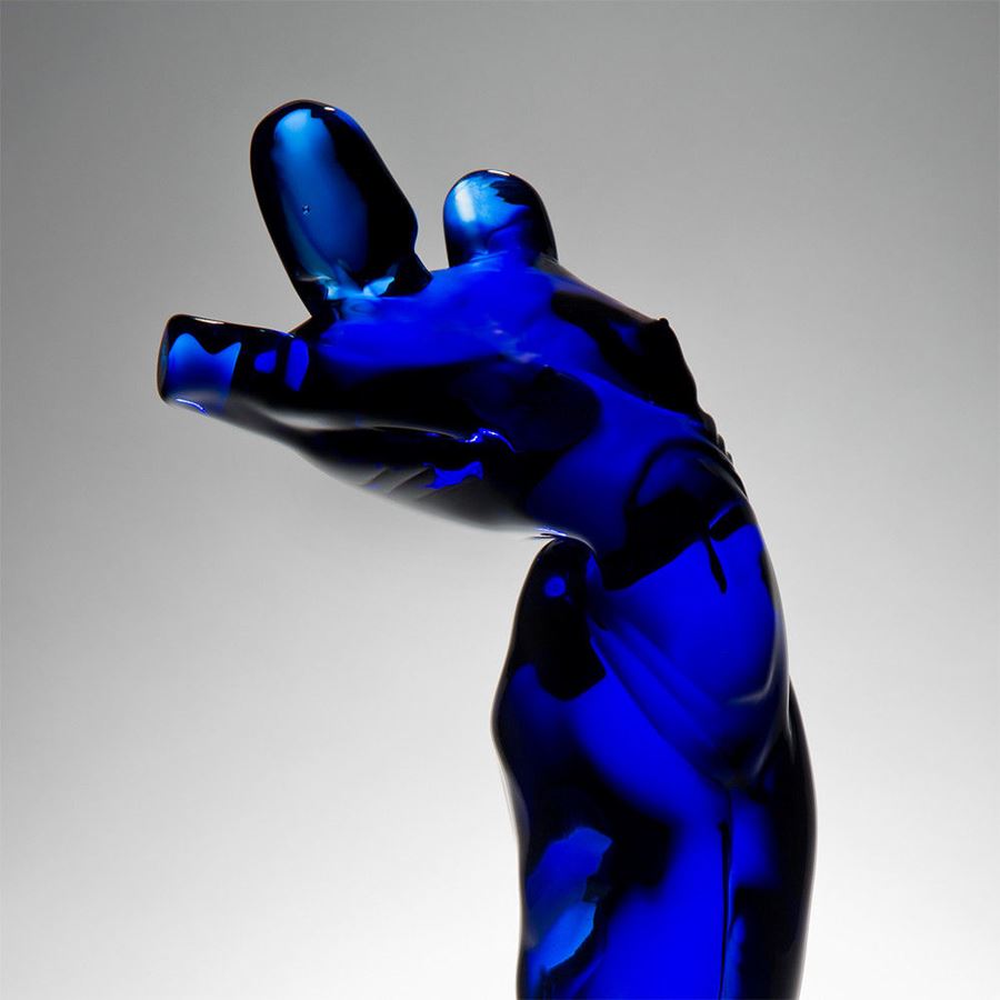 abstract blue glass sculpture of body-like shape on black base