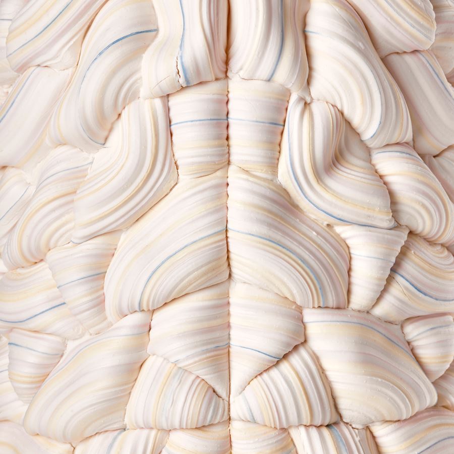 stacked sculptural vessel made up of interwoven sugary ridged rings in white with bands of soft pastel colours with front seam and the two halves mirroring each other