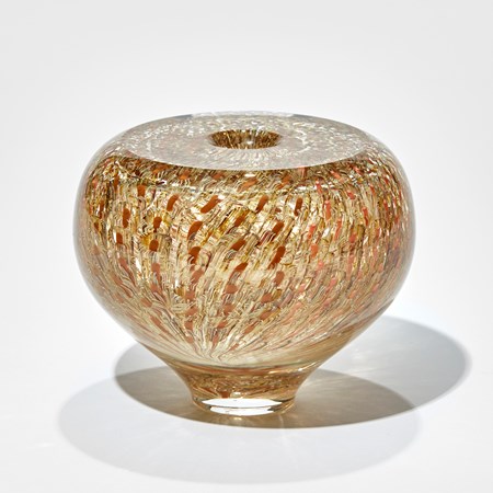 small round clear vase with top flat surface and tapered foot with trapped repeat surface pattern in gold brown orange salmon and amber hand made in glass