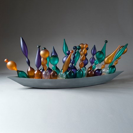 thin art glass sculpted objects in orange purple and green in long grey tray