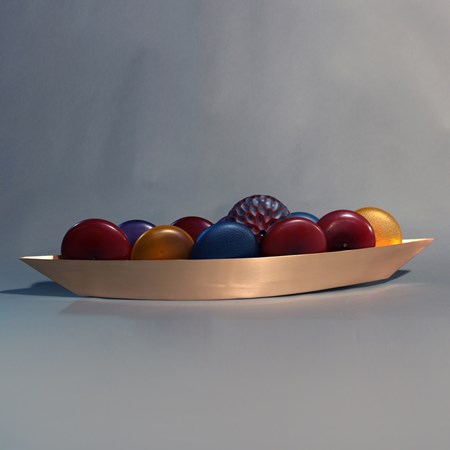 glass artwork of red blue and yellow balls inside steel tray