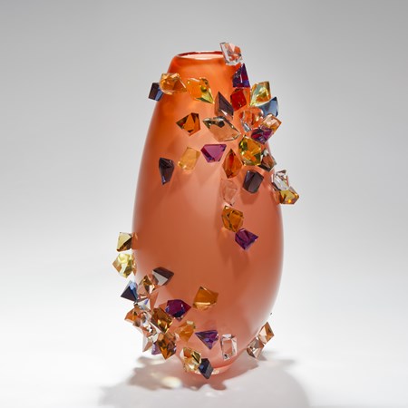 tall handblown glass-art case in peach with colored crystals adorning the outer edges