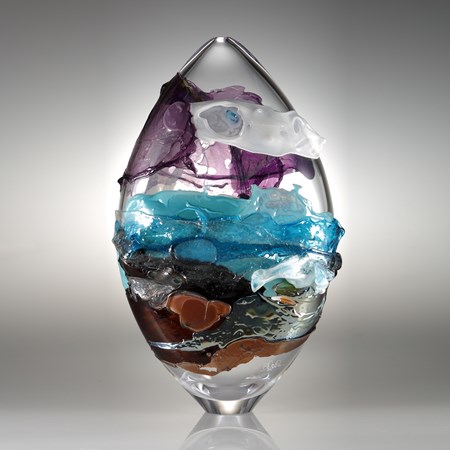 oval shaped handblown clear glass sculpture with purple blue and orange splashes