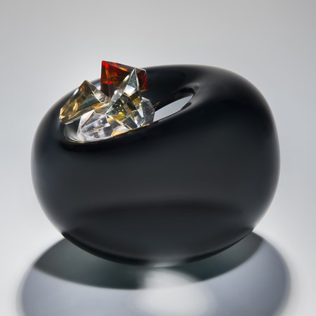 blown glass vase in black in the shape of an apple with red white and gold crystal additions