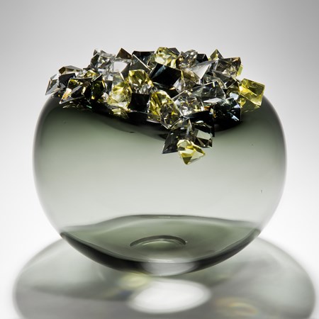 handblown spherical glass vessel in grey and green with grey black and yellow glass crystals on top