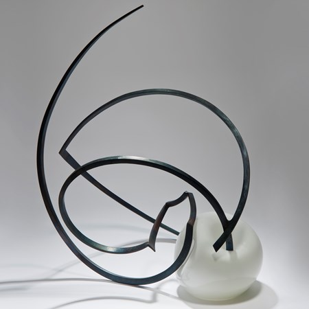 abstractly shaped pearl coloured glass sphere with asymmetrical mangled long thin black metal rod sprouting from the centre