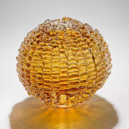 sphere shaped blown glass sculpture in amber made from stacked small shards