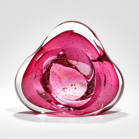 soft triangular glass sculpture with clear outer and bright pink inner layer containing trapped small fragments of 24 carat gold
