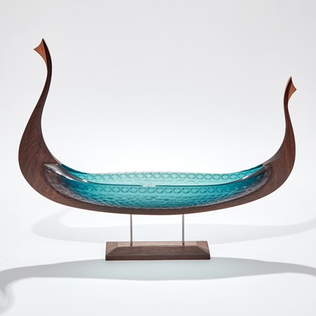 viking ship made from hand carved oak and handblown teal coloured glass with circular cutting detail raised up in a stand