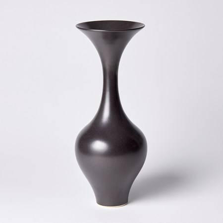 black classic in shape vase with round base long slim neck and trumpet flaring rim hand thrown from porcelain and glazed