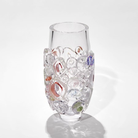 clear cylinder vase with relief raised patterns in different shaped rings with pink purple and olive details hand made from blown glass