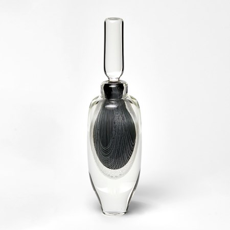 tall clear bottle with stopper with internally trapped fine filigree pattern in white over black hand made from glass