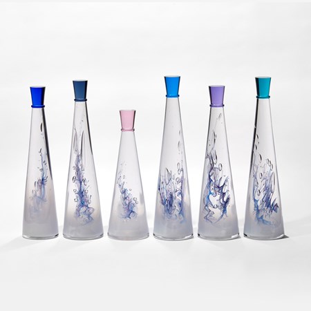 set of six conical tall bottles with fading interior from white to clear and blue lined helix detail each with a different coloured stopper hand made form glass