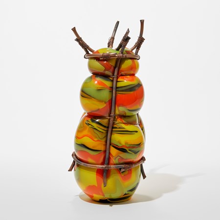 opaque lime green yellow red and black blown glass sculpture held within and bulging between a bound copper cage with top crown of copper tubes