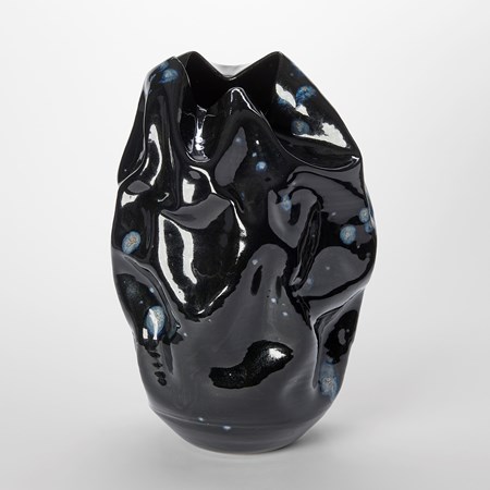 crumpled wrinkled and undulating vessel with glossy black surface with blue ink blot irregular details hand made from ceramics