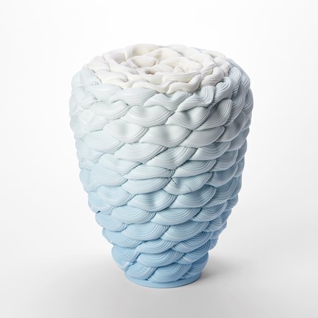 inverted teardrop standing vessel with small top opening and with the appearance as if made from stacked soft loops of ridged clay with a blue base fading to the top which is white hand made from parian porcelain