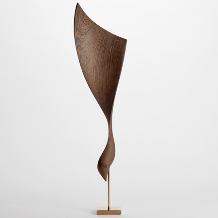 abstract curved highly grained wenge wood sculpture with lower curled section and upper wider sail form with fine gold inlaid detail and held aloft on a gold plated stand