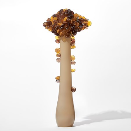 tall abstract tree sculpture with long opaque bronze trunk with diamond shaped canopy covered in lollipop shaped leaves in amber and brown handmade from glass
