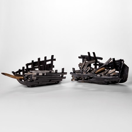black and bronze hued glass sculpture resembling two halves of a sunken aged ship wreck with split hull and old sea worn timbers