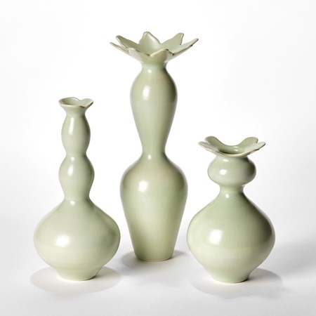 group of three porcelain vases with undulating forms in soft green with abstract cactus flowers around the top rims