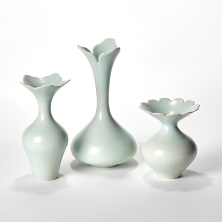 still life of three celadon coloured porcelain vases with rounded wide bases reaching to slender necks each with abstract flower opening rims