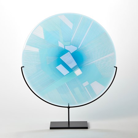 turquoise and blue etched glass plate with raised graphic abstract pattern on a black metal base