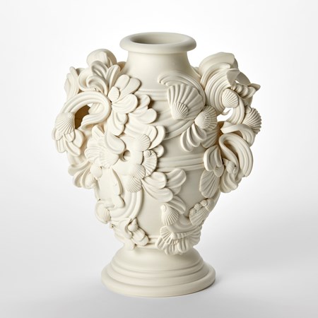 porcelain sculptural vessel with a wide round ridged foot ring flaring central shape with two handles with the surface covered in architectural swirls and shells