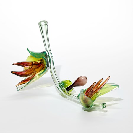 exotic plant inspired sculptural artwork with light green transparent organic curving stem with lime green leaves containing dark amber red finger shaped stamen hand made from glass