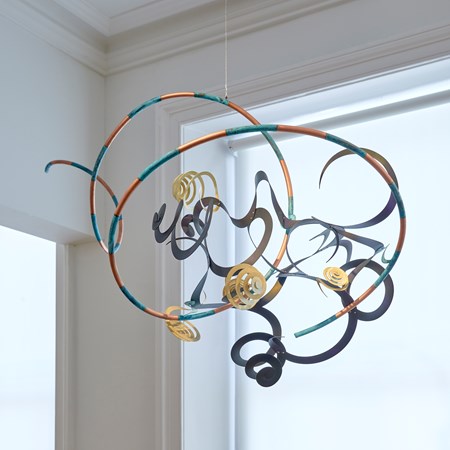 hanging kite inspired sculpture consisting of striped ribbons and curls made from hand painted copper oxydyed aluminium & brass in dark midnight indigo blue orange silver and aqua with verdigris