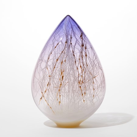 pointed teardrop shaped glass sculpture with opaque vanilla coloured base fading to transparent then to lilac with the interior filled with an organic lattice of traversing fine canes in white and bobbly ones in gold