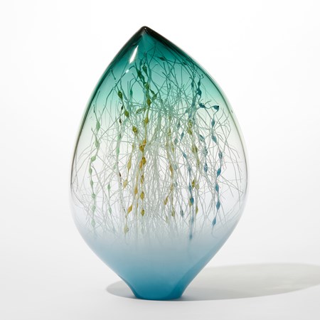 off centre glass ovoid sculpture with opaque light blue base transparent middle and sea green transparent top with the interior filled with a mass of fine straight and undulating canes in white ochre blue and teal