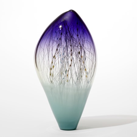 off centre tall ovoid glass sculpture with opaque soft turquoise base fading to clear with a pointy transparent intense purple top with the inside filled with fine straight and undulating canes in ochre brown teal white and blue