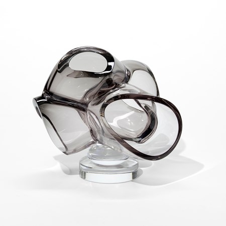 small clear stand with a cluster of uneven organic squashed grey transparent bubbles with cut open fronts amassed on the top hand blown from glass