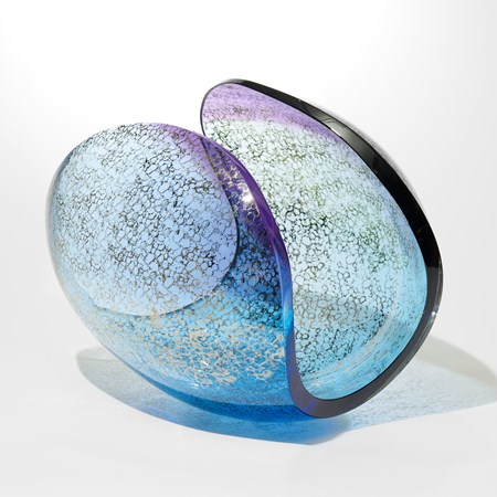 round transparent blue and purple sculpture with elliptical cut away section hand made from glass with a platinum sponged pattern on the outside