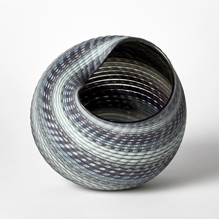 textured and woven in appearance shell like vessel with matt exterior and shiny interior with bands of colour in steel blue jade grey and aqua hand made from glass
