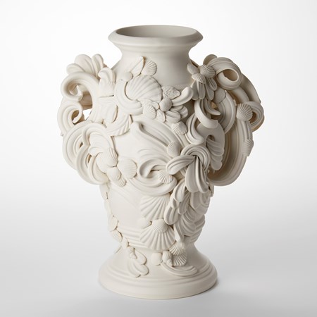 classically shaped urn with turned foot and top opening with barrel rounded middle and two handles on each side with the surface adorned with organic rococo flourishes swirls shells and leaves