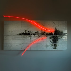 white landscape panel with tiled effect and a black smudged organic mass across the middle and two sweeping lines in bright neon hand made from glass