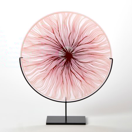 round glass rondel in red pink and clear with cut wavy lines emanating from the centre hand made from glass and presented on a matt black steel stand