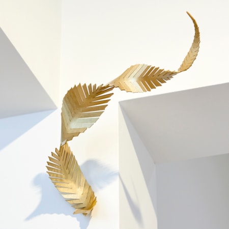 abstract angular curling feather with straight slits along the length and curling twisting form with a brushed finish and wall mounted as it just touching the surface